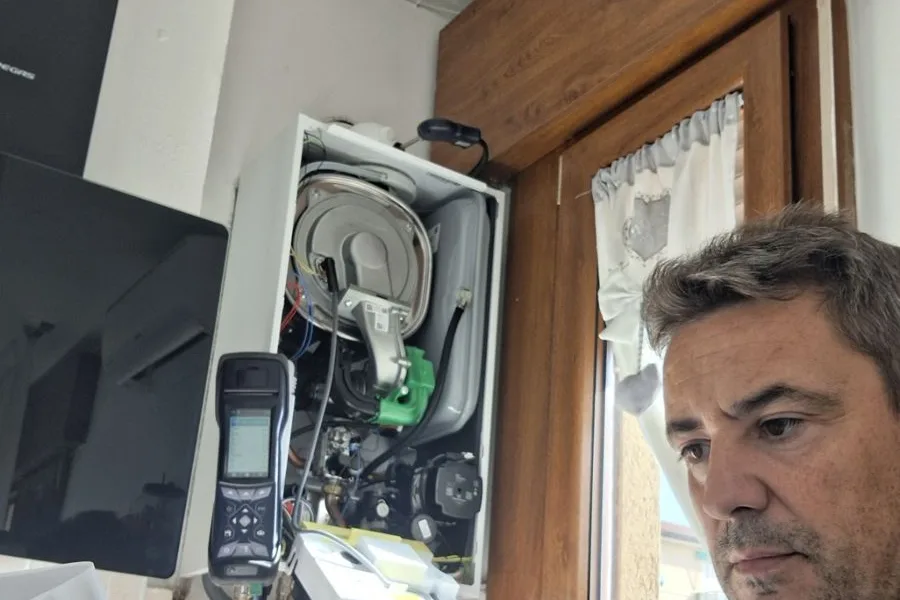 Emanuele Frison durante la messa in servizio di una caldaia a condensazione, con l’analizzatore fumi collegato